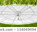 the structural steel framework that forms the main core of a modern dome-style fabric roof. It highlights both strength and contemporary design, surrounded by lush, vibrant greenery 134049094