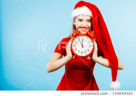 Woman wearing Santa Claus costume holding clock Woman wearing Santa Claus costume holding clock 134049383