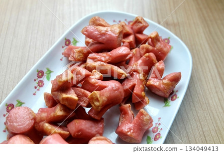 Decorative Fried Pink Sausages on White Platter 134049413