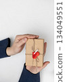 Person Holding Wrapped Gift With Red Heart for Saint Valentine's Day 134049551