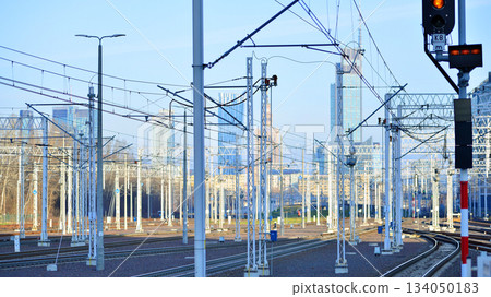 Tracks and electric high voltage for electric trains wires on reinforced concrete and metal masts against the backdrop of a city skyscrapers on a winter day. 134050183