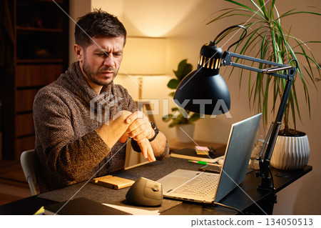 Man sitting at desk with wrist pain during remote work 134050513