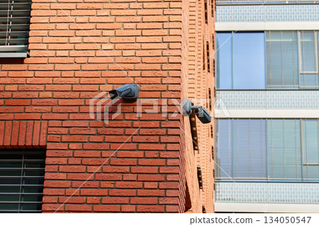 Surveillance camera mounted on a red brick wall exterior Surveillance camera mounted on a red brick wall exterior 134050547