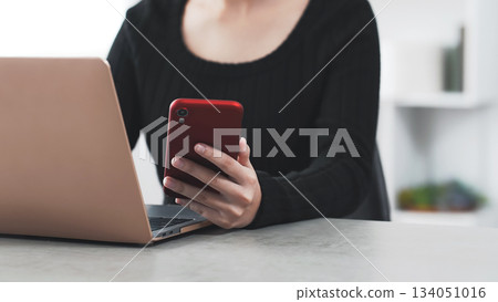 A woman working on a laptop and smartphone A woman working on a laptop and smartphone 134051016