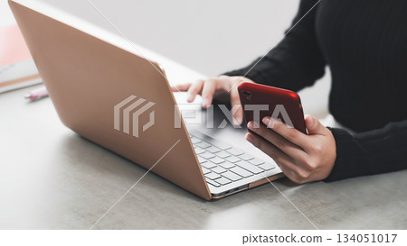 A woman working on a laptop and smartphone A woman working on a laptop and smartphone 134051017