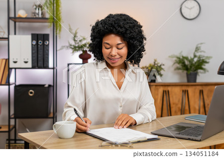 African American businesswoman signs important documents nods satisfied closing big successful deal African American businesswoman signs important documents nods satisfied closing big successful deal 134051184