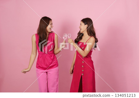 Party Fun. Two friends toasting with drinks in a cheerful pink backdrop. Party Fun. Two friends toasting with drinks in a cheerful pink backdrop. 134051213