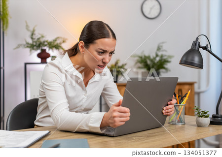 Young businesswoman sees laptop hang presses keys but computer fails to respond frustrated halt hard 134051377