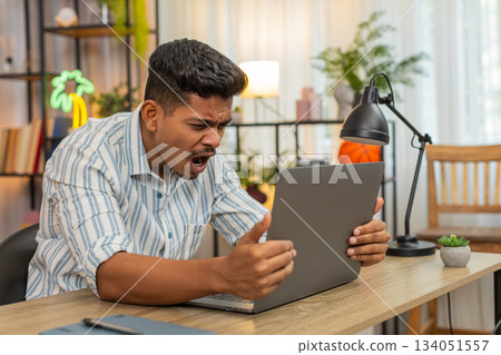 Indian man reads bad project news on laptop sighs feels defeat loss failure after overdue deadline Indian man reads bad project news on laptop sighs feels defeat loss failure after overdue deadline 134051557