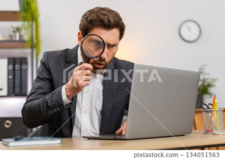 Middle-aged businessman auditor uses magnifier to zoom tiny font on laptop finds mistake satisfied Middle-aged businessman auditor uses magnifier to zoom tiny font on laptop finds mistake satisfied 134051563