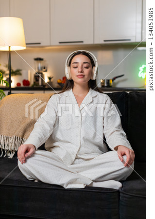 Young woman in headphones listens rain audio meditates calm breathing quiet focus inner peace relax 134051985