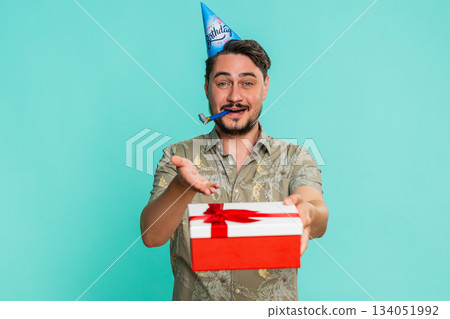 Adult man in party hat smiling happily giving birthday gift to someone celebrating event generosity 134051992