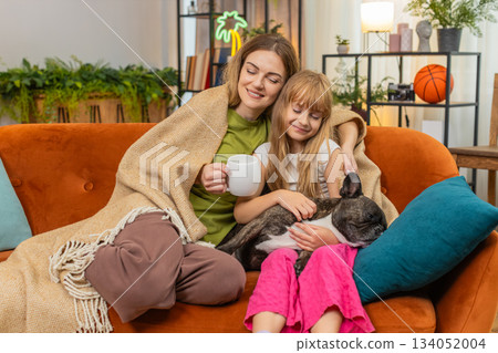 Mother daughter dog share tea and blanket relax together cozy rest hug smile comfort family evening Mother daughter dog share tea and blanket relax together cozy rest hug smile comfort family evening 134052004