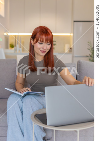 Young woman opens laptop and notebook starts weekly planning writes goals and task schedule for week Young woman opens laptop and notebook starts weekly planning writes goals and task schedule for week 134052005