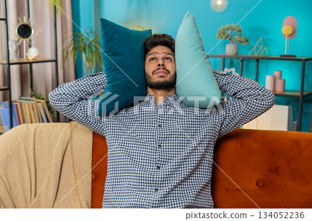 Neighbors repair work irritated man by loud music at home cover ears with pillows annoyed by noise 134052236