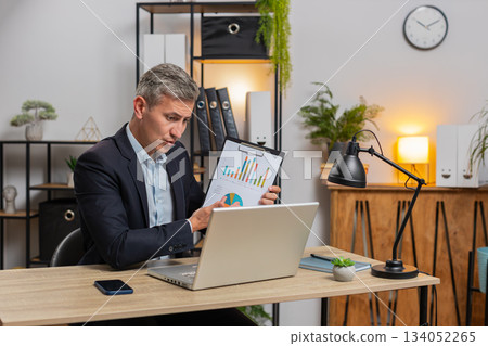 Confident young freelancer shows graphical analytics during video call on laptop at office desk Confident young freelancer shows graphical analytics during video call on laptop at office desk 134052265