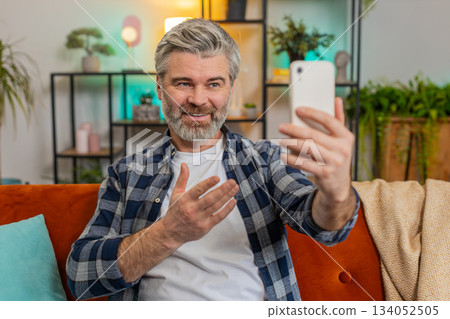 Senior man making video call with wave happy chat and communication on internet online app at home 134052505
