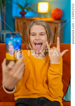 Teenager boy blogger taking selfie with smartphone, making funny facial expressions, posing at home 134052552
