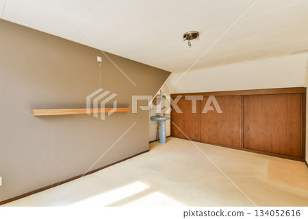A minimalist interior featuring a wooden shelf and cabinets with a neutral color palette. The room exudes simplicity and elegance, ideal for various design ideas. 134052616
