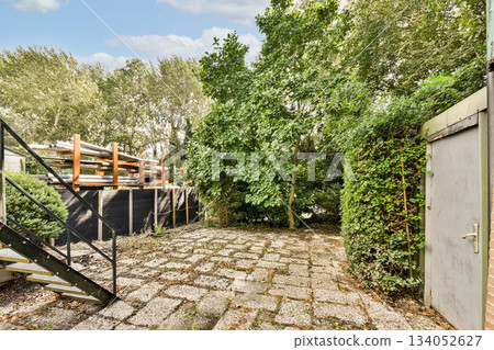 A serene outdoor area featuring vibrant greenery, stone pathways, and an inviting atmosphere. Perfect for relaxation and enjoying nature. 134052627