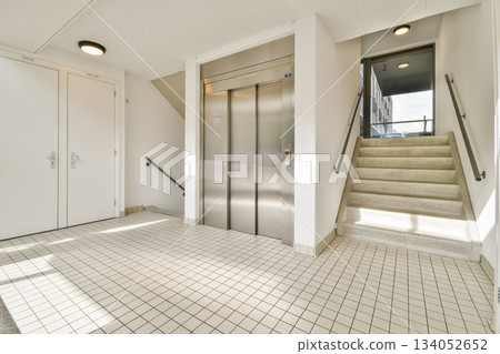 A clean and modern interior space featuring a staircase and an elevator. Natural light streams through the windows, enhancing the contemporary design. A clean and modern interior space featuring a staircase and an elevator. Natural light streams through the windows, enhancing the contemporary design. 134052652