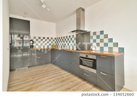 A sleek modern kitchen featuring stylish cabinets, minimalist design, and a striking backsplash that enhances the contemporary aesthetic. Ideal for culinary enthusiasts. 134052660