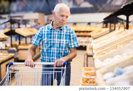 old age senor examines bakery products in the grocery section of the supermarket old age senor examines bakery products in the grocery section of the supermarket 134052907