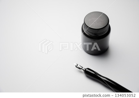 An ink bottle and a fountain pen with a removable cartridge lie on a white background. There is empty space for text and advertising An ink bottle and a fountain pen with a removable cartridge lie on a white background. There is empty space for text and advertising 134053052