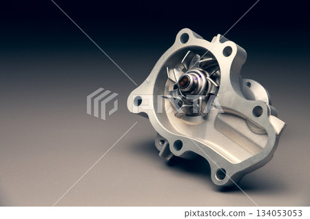 A new, shiny aluminum engine coolant pump on a gray gradient background. Contrast backlighting. A new, shiny aluminum engine coolant pump on a gray gradient background. Contrast backlighting. 134053053