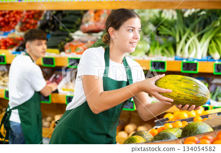 Young female seller puts melons on the counter Young female seller puts melons on the counter 134054582