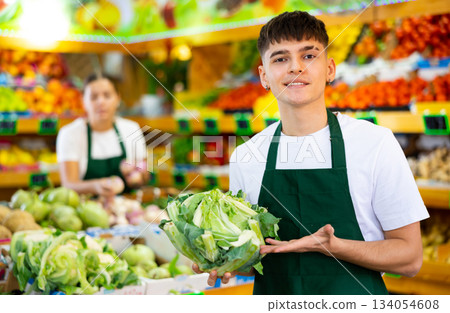 Portrait of a guy seller, holding a cabbage in his hands 134054608