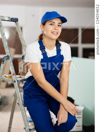 Smiling young female builder in blue uniform at construction site 134054652