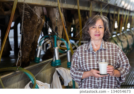 Mature female milker posing with glass of milk Mature female milker posing with glass of milk 134054673
