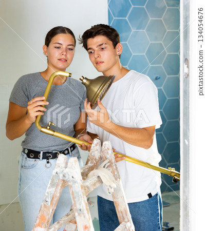 Young couple assembling shower before fixing to wall in apartment during refurbishment Young couple assembling shower before fixing to wall in apartment during refurbishment 134054676
