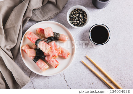 Crab sticks in rice paper with nori fried in oil on a plate on the table top view Crab sticks in rice paper with nori fried in oil on a plate on the table top view 134054928