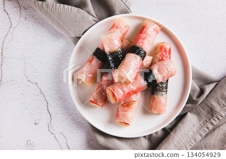 Close up of crab sticks in rice paper with nori fried in oil on a plate on the table top view Close up of crab sticks in rice paper with nori fried in oil on a plate on the table top view 134054929
