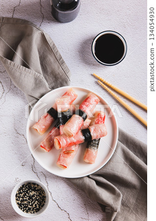 Fried spring rolls with crab sticks and nori on a plate on the table top and vertical view Fried spring rolls with crab sticks and nori on a plate on the table top and vertical view 134054930