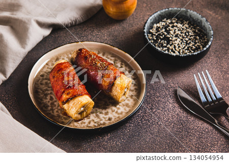 Sweet and Savory Baked Banana Wrapped in Bacon on a Plate on the Table 134054954
