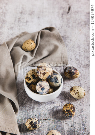Fresh unpeeled quail eggs in a bowl and on the table vertical view Fresh unpeeled quail eggs in a bowl and on the table vertical view 134054974