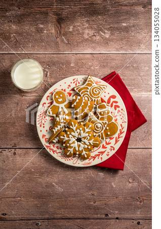 Holiday background. Christmas gingerbread cookies in a plate with glass of milk. Flat lay Holiday background. Christmas gingerbread cookies in a plate with glass of milk. Flat lay 134055028