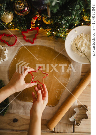 Holiday background. Woman holding cookie star cuter, cooking Christmas gingerbread cookies. Top view Holiday background. Woman holding cookie star cuter, cooking Christmas gingerbread cookies. Top view 134055048