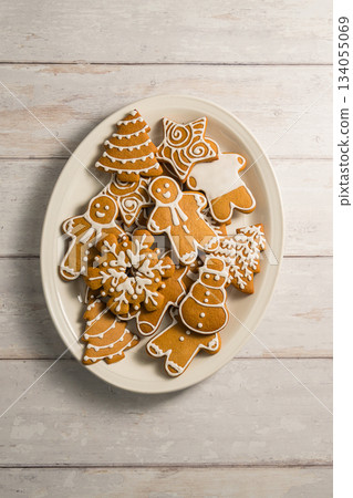 Holiday background. Christmas gingerbread cookies in different shapes in a plate, top view. Holiday background. Christmas gingerbread cookies in different shapes in a plate, top view. 134055069