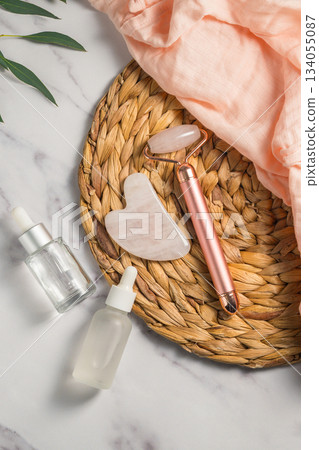 Rose quartz gua sha and massage roller tool for face massage and oil bottles, abstract beauty photo Rose quartz gua sha and massage roller tool for face massage and oil bottles, abstract beauty photo 134055087