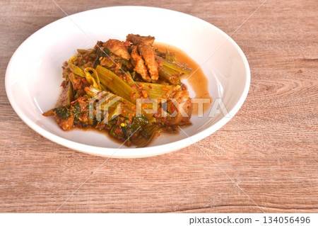 spicy stir fried Thai morning glory with slice fat pork belly in curry sauce on plate spicy stir fried Thai morning glory with slice fat pork belly in curry sauce on plate 134056496