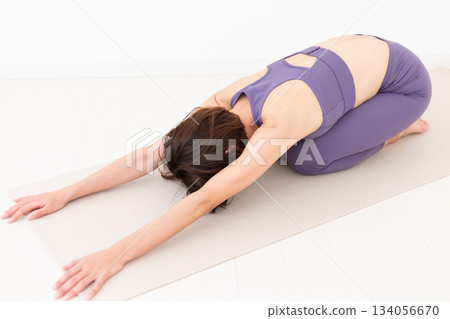 一位身穿瑜伽服的中年婦女在家中做瑜伽 134056670