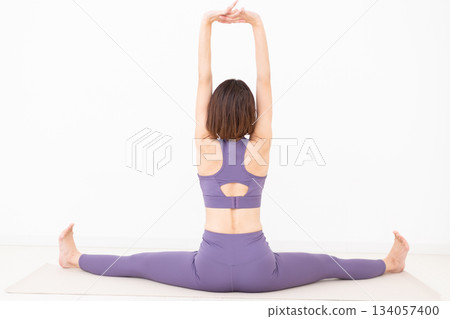 Middle-aged woman in yoga wear stretching at home Middle-aged woman in yoga wear stretching at home 134057400