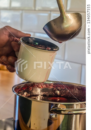 Pouring Hot Berry Drink from Pot Into Mug Pouring Hot Berry Drink from Pot Into Mug 134057555