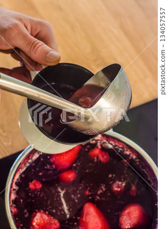 Ladling Hot Berry Drink Into Mug 134057557