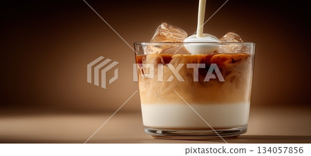 Milk pouring into a glass cup of black coffee, creating a dynamic splash and creamy layers. Milk pouring into coffee creating splash and swirl Milk pouring into a glass cup of black coffee, creating a dynamic splash and creamy layers. Milk pouring into coffee creating splash and swirl 134057856
