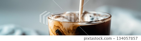 Milk pouring into a glass cup of black coffee, creating a dynamic splash and creamy layers. Milk pouring into coffee creating splash and swirl Milk pouring into a glass cup of black coffee, creating a dynamic splash and creamy layers. Milk pouring into coffee creating splash and swirl 134057857